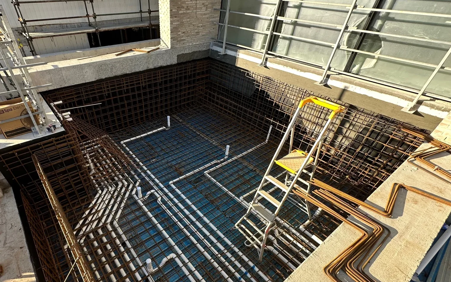 Whole elevated pool structure integrated with a building, showing steel reinforcement and in-shell plumbing.