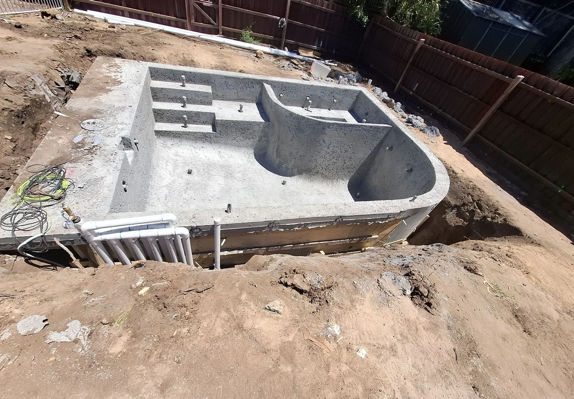 Whole structural concrete shell in Portsea with a curved round spa, integrated steps and internal ledges.