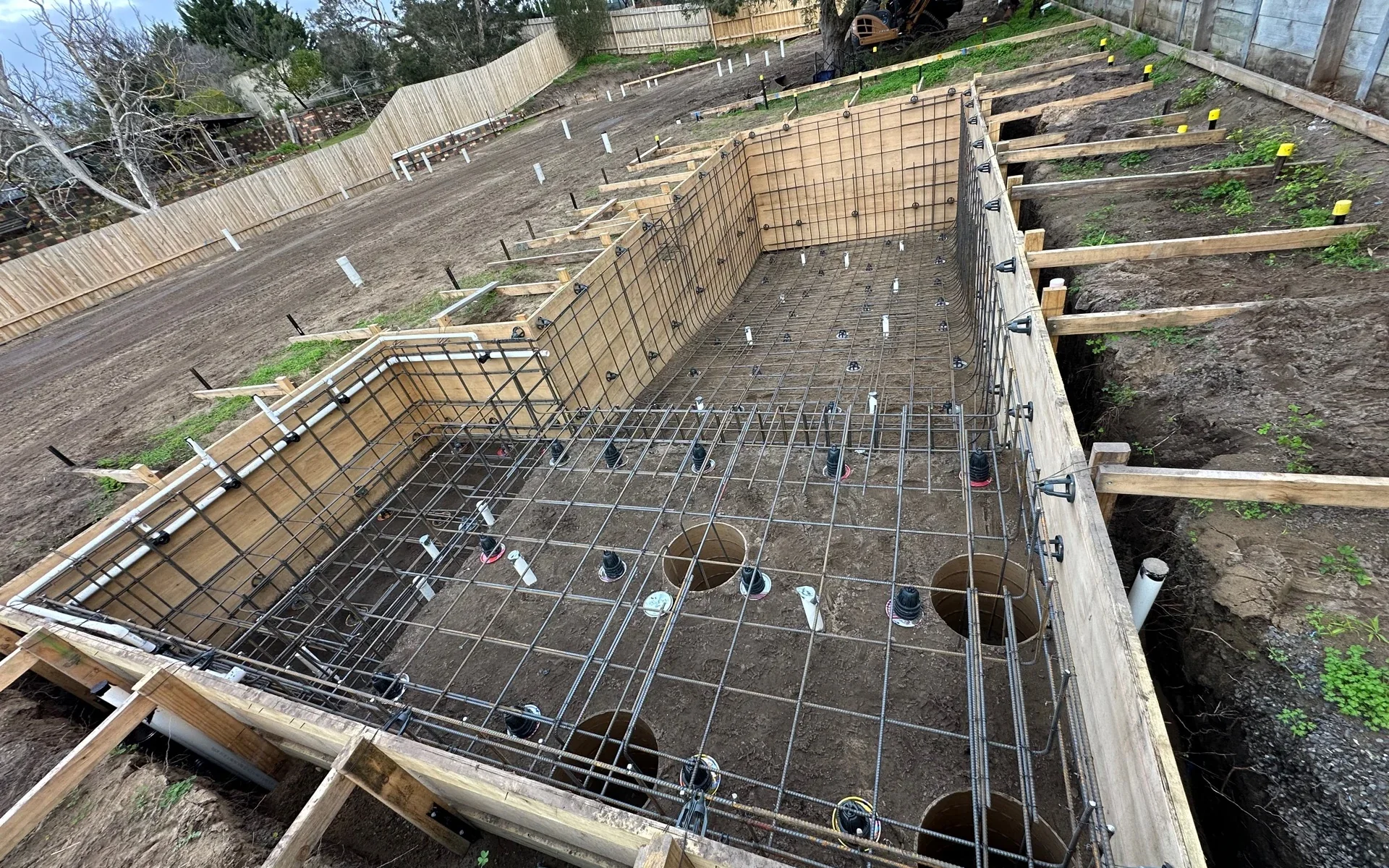 Whole long narrow pool and spa structure with formwork, reinforcement and in-shell services before concrete placement.