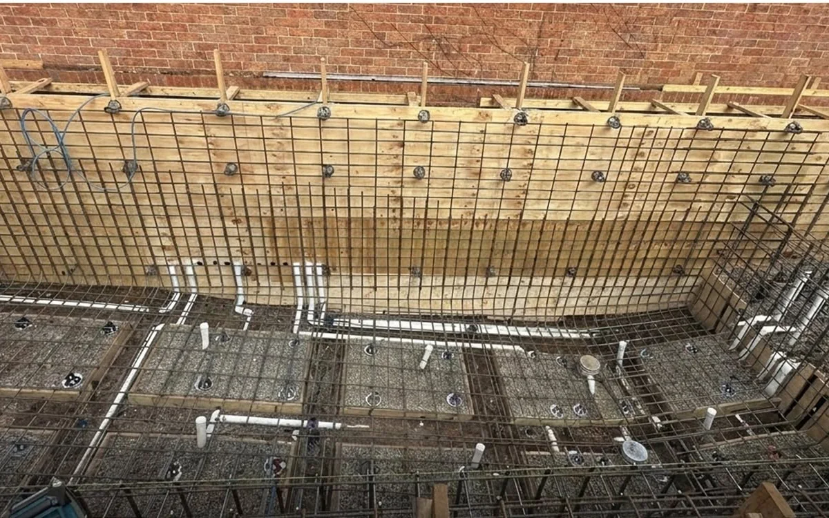Reinforcement, pool wall steel and in-shell plumbing prepared within structural formwork.